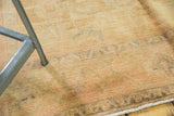 Distressed vintage Oushak rug pile with even wear, faded ivory, pale gold, and blush floral motifs.