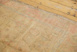 Distressed vintage Oushak rug texture with even wear, revealing faint ivory, pink, and gold motifs.