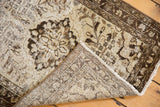 Distressed beige and charcoal floral pile of a Hamadan rug, revealing its hand-knotted foundation and fringe.