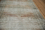Distressed texture of antique Persian Kerman runner, with pale bronze and faded floral patterns.