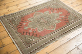Corner view of distressed Oushak rug, highlighting geometric border and worn blush red pile.