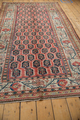 Antique Kurdish runner's cinnabar field with repeating floral botehs and ivory border detail.
