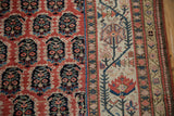 Antique Kurdish runner displaying cinnabar red boteh field and ivory border with stylized tree motifs.