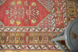 Vintage Melas rug outer border featuring elongated motifs in pale bronze and cinnabar red.