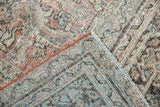 Vintage distressed Mahal carpet corner showing soft hues, textural wear, and a rust-orange side binding.