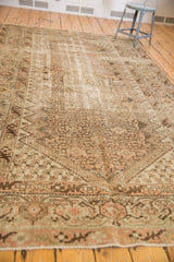 Distressed Malayer carpet corner with faded traditional floral patterns in blush and chocolate brown.