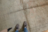 Soft pile and faded geometric details on distressed Oushak rug with muted hues.