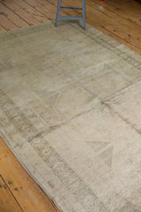Distressed texture revealing subtle geometric motifs on a vintage Oushak rug in muted silver and ivory.