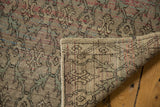 Distressed Oushak rug with mostly even wear, corner folded revealing trellis pattern on reverse.