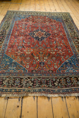 Fringe, bronze charcoal border, and ruby red field with intricate floral Herati motifs.