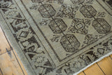 Distressed Oushak rug runner end, highlighting geometric guls, wide border, and secured fringe.
