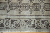 Distressed Oushak rug with geometric guls and charcoal black border, revealing even pile wear.
