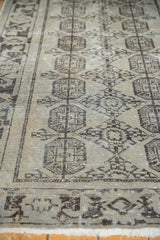 Distressed Oushak rug detail: charcoal geometric guls on ivory field with faint foundation showing.
