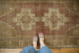 Distressed Oushak rug with textured low pile, showing mauve and beige geometric medallion.