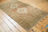Distressed vintage Oushak rug detail: abrashed dusty plum field with geometric stepped medallion.