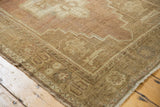 Vintage distressed Oushak rug corner detailing geometric border, low pile, and subtle plum tones.
