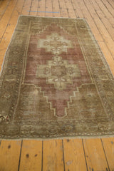 Secured fringe and distressed low pile of a plum and beige vintage Oushak rug.