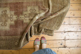 Distressed vintage Oushak rug showing soft, pliable texture and geometric forms in plum and sand.