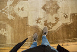 Textured distressed Oushak carpet with bronze and beige abrashes and primitive motifs.