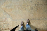 Distressed Oushak carpet field showing even wear, pale dusty gold, and subtle beige patterns.
