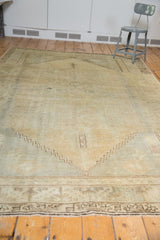 Distressed vintage Oushak carpet showing chocolate brown geometric border and secured fringe.