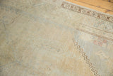 Faded distressed Oushak rug corner with brown zigzag, abstract border, and faint red motifs.
