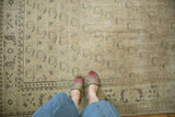 Distressed vintage Oushak carpet, showing ivory and pale green boteh with foundation showing through.