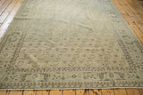 Distressed Vintage Oushak carpet corner, showing ivory, green boteh pattern, and foundation wear.