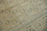 Distressed Oushak rug pile, revealing faded ivory, green, and brown boteh motifs.