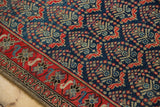 Red border with sky blue florals, navy field with oversized boteh design on vintage Malayer rug.