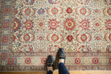 Distressed ivory field with cinnabar red palmettes and intricate floral border.