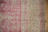 Distressed Sivas carpet, faded fuchsia and platinum vinery, with visible foundation.