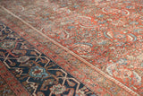 Vintage Heriz carpet detail: brick red Herati field, dusty navy border, soft wear.