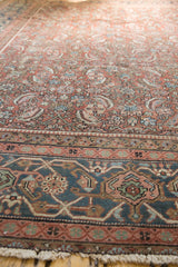Detail of vintage Heriz carpet, showing Herati pattern, dusty navy border, and light pile wear.