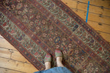 Visible wear exposing foundation on the Persian Kurdish runner with faded raspberry and teal vinery.