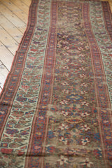 Antique Kurdish runner's worn pile displaying geometric vinery, starburst flowers, and visible foundation.
