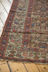 Hand-knotted antique Kurdish runner's fringed end, showing time-softened pile and geometric vinery.