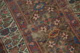 Faded geometric starbursts, dusty gold, and exposed foundation of an antique Kurdish runner.