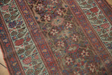 Faded raspberry, teal, and ivory geometric border with visible foundation wear on an antique Kurdish runner.