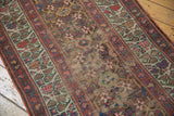 Close view of antique Kurdish runner showing worn pile, exposed foundation, geometric vinery.