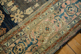 Intricate floral palmettes and curvilinear vine motifs in dusty blush and navy on antique Farahan Sarouk.