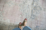 Distressed Oushak rug, faded mauve, teal, and exposed knot heads, with feet.