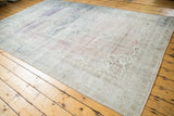 Distressed Oushak rug corner showing trefoil spandrels, muted colors, and wear to foundation.