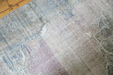 Distressed Oushak rug detail with exposed knot heads, faded mauve, purple, and teal colors.