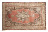 Distressed Oushak rug with cinnabar red quatrefoil medallion, antique ivory, and time-softened tones.