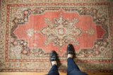 Vintage Oushak rug, distressed with cinnabar red medallion and book cover spandrels.