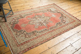Distressed Oushak rug corner, showing cinnabar red field, antique ivory book cover spandrel, and wear.