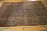 Antique Belouch rug border with geometric motifs in chestnut brown, black cherry red, and navy blue, showing even wear.