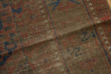 Tone-on-tone chestnut brown, black cherry red, and navy blue pile of antique Belouch carpet, featuring serrated gul motifs.
