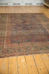 Antique Belouch carpet: serrated gul motifs in black cherry, navy, and chestnut brown.